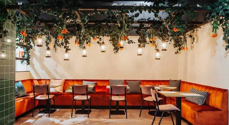 Oranje hoekbank onder hangende planten en lantaarns in een Ekmekci-vestiging