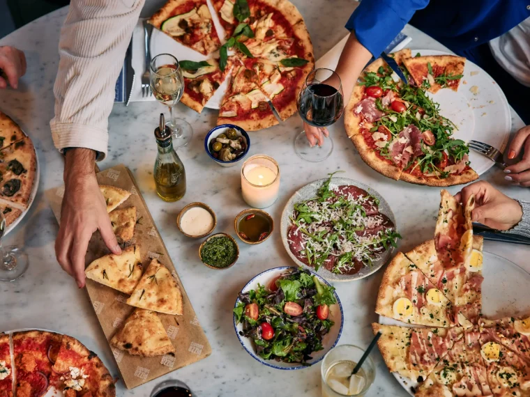 Een gedekte tafel met pizza's bij De Pizzabakkers